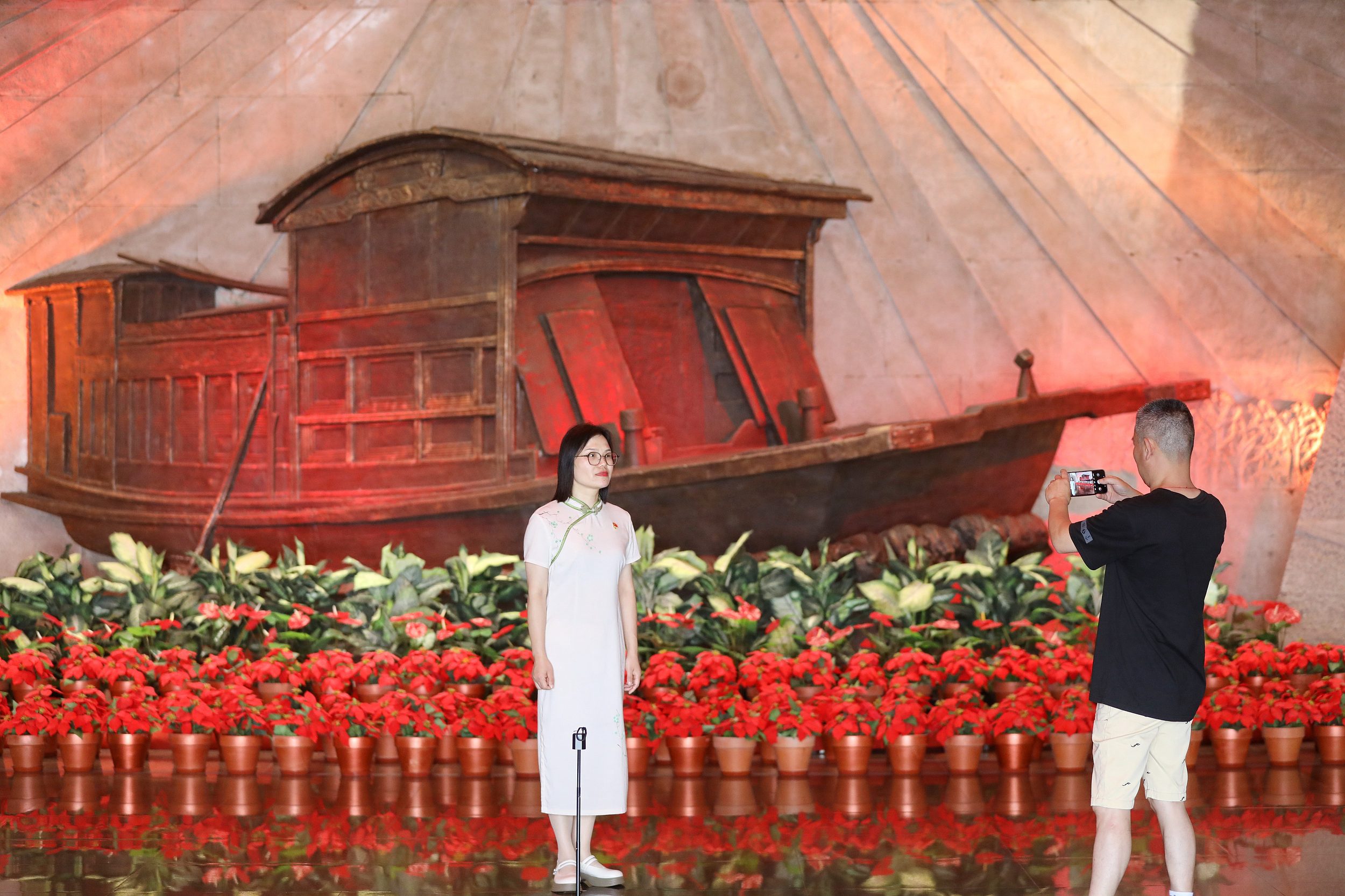 2025年6月24日，浙江嘉興，游客在南湖革命紀(jì)念館與紅船雕塑合影。（圖片來源：視覺中國）